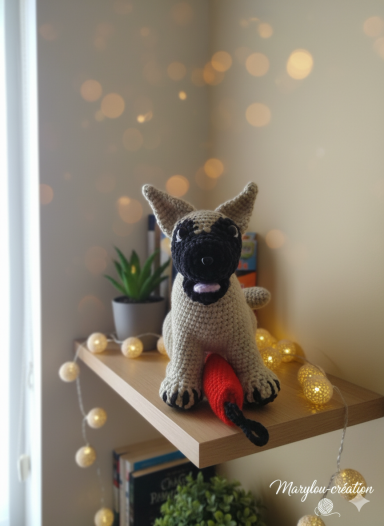 Malinois fait main au crochet selon la photo du chien Un chiot en peluche sur une étagère, décoré de lumières et d'une plante.